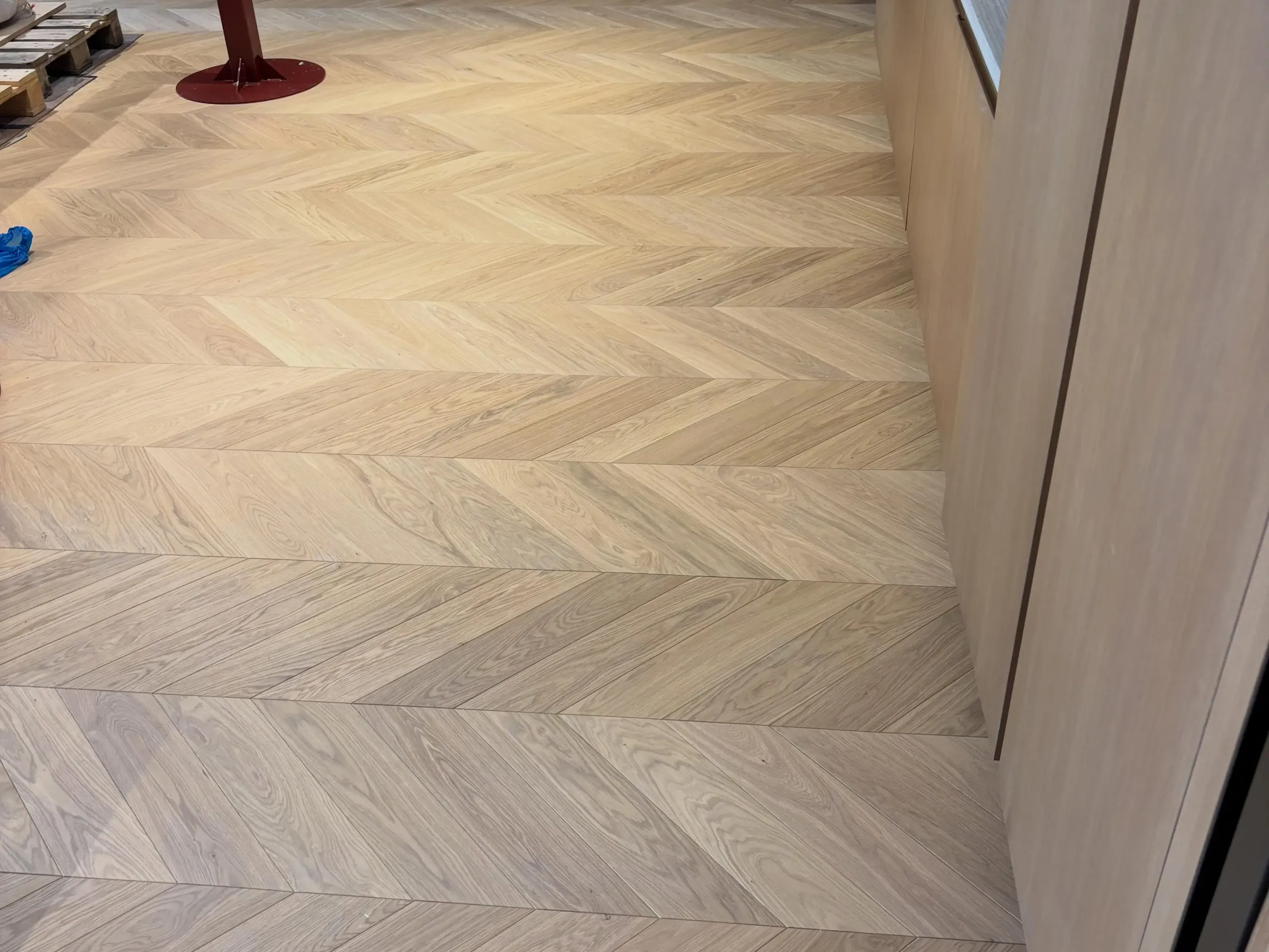 A pale chevron timber floor laid up to a wall